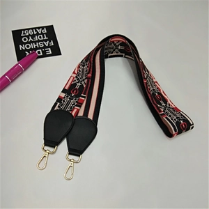 Close-up of ethnic style woven bag strap with red heart pattern and golden hooks
