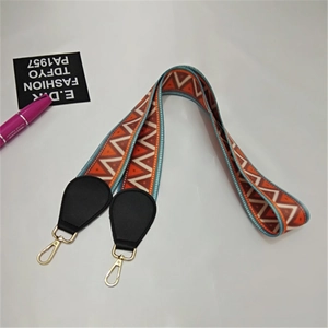 Close-up of ethnic style woven strap with orange geometric patterns and gold lobster clasp