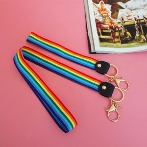 Rainbow striped neck lanyard with golden metal ring and lobster clasp on pink background