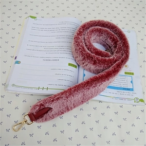 Detail of faux fur strap with red leather connectors and golden metal lobster clasps
