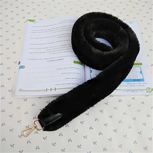 Close-up of fluffy black faux fur bag strap with gold metal carabiner clasps