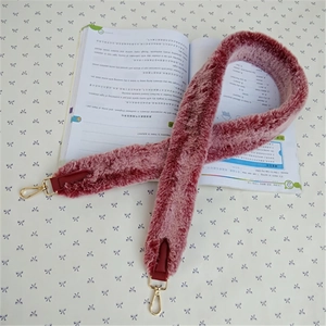 Close-up of plush faux rabbit fur shoulder strap in dark pink with gold metal buckles