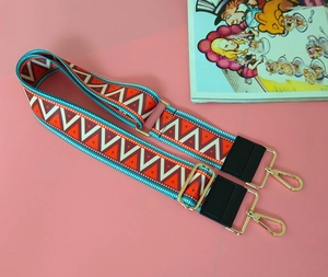 Close-up of bohemian geometric woven bag strap with leather ends and golden metal clips