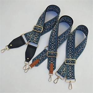 Detail of ethnic geometric embroidery on wide adjustable bag straps with gold metal hardware