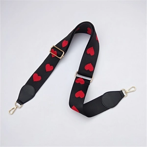 Adjustable black woven bag strap with red heart pattern and gold metal hooks for handbags