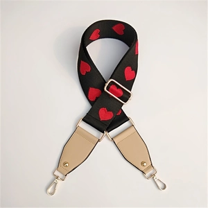 Macro shot of wide black shoulder strap with red heart embroidery and gold metal clips