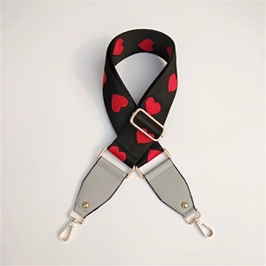Detail of embroidered red heart pattern on wide black fabric bag strap with gold hooks
