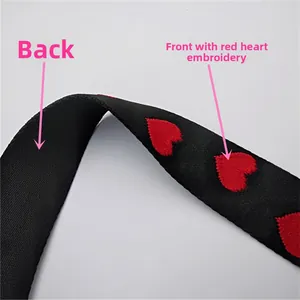 Detail of red heart embroidery on a premium thick black adjustable woven bag strap