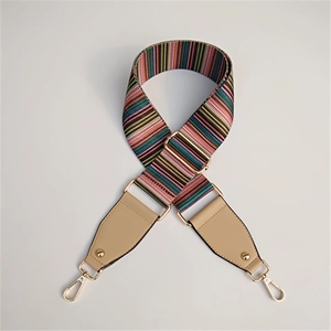 Close-up of colorful striped wide woven shoulder strap with gold metal hooks and leather detail