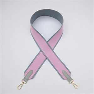 Detail of pink woven bag strap with grey leather ends and golden metal lobster clasps