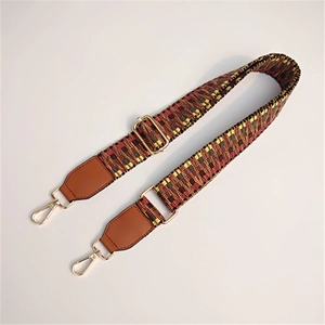 Close-up of ethnic geometric woven bag strap with leather ends and golden metal hardware