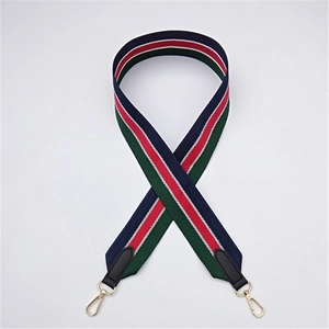 Detailed view of striped fabric bag strap with black leather ends and golden metal clips