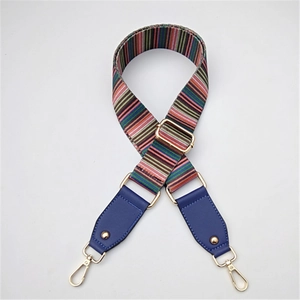 Close-up of colorful striped canvas bag strap with blue leather ends and gold metal buckles