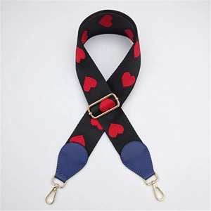 Detail of embroidered red hearts on black strap with blue leather and gold metal hooks