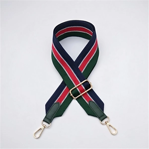 Détail de la bandoulière rayée réglable avec mousquetons dorés et embouts en cuir vert