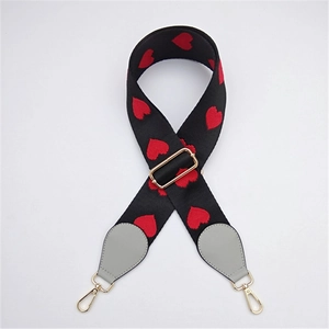 Macro detail of black woven bag strap with red heart embroidery and golden metal buckles
