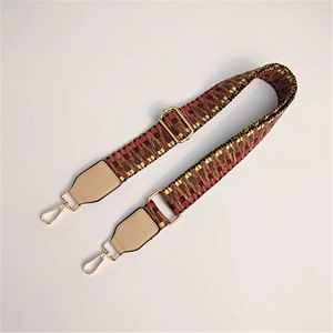 Detail of adjustable woven handbag strap with colorful geometric pattern and gold buckles