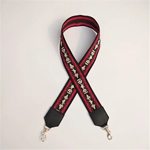Close-up of ethnic woven handbag strap with red stripes and gold metal buckles