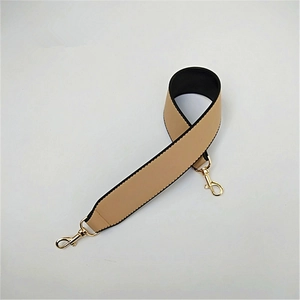 Detail of widened PU leather bag strap in beige and black with golden lobster clasps