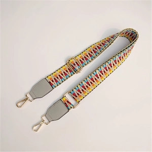 Close-up of colorful woven geometric strap with grey leather ends and gold metal hooks