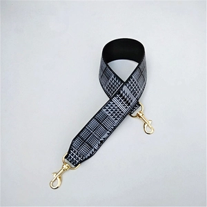 Detail of wide black and white houndstooth strap with gold swivel metal hooks for handbags