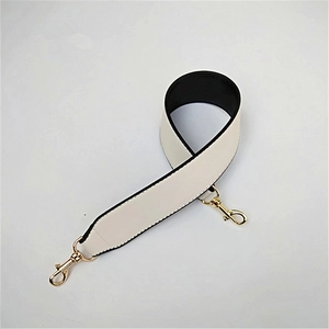 Detail of cream PU leather bag strap with black edges and gold metal swivel clasps