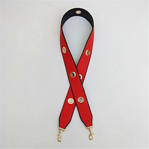 Detail of red wide shoulder strap with gold metal eyelets and rotating hooks