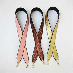 Close-up of three wide glitter shoulder straps in pink, brown and gold with metal hooks
