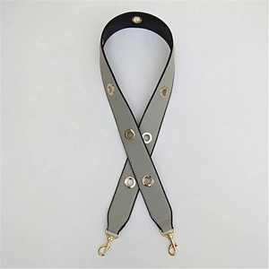 Detail of grey PU leather bag strap featuring gold metal eyelets and lobster clasps