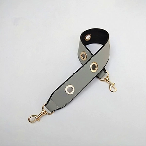 Close-up of wide grey PU shoulder strap with gold metal eyelets and swivel lobster clasps