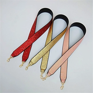 Detail of wide glitter shoulder straps in red gold and pink with gold lobster clasps