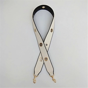 Detail of cream white leather bag strap with golden eyelets and lobster clasps