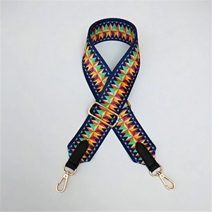 Close-up of colorful geometric woven bag strap with golden metal hooks and buckles