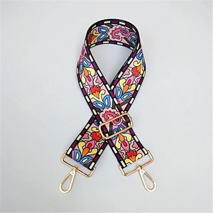 Adjustable bohemian floral woven bag strap with golden metal clips on gray background