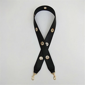 Detail of black PU shoulder strap with gold eyelets and rotatable metal lobster clasps