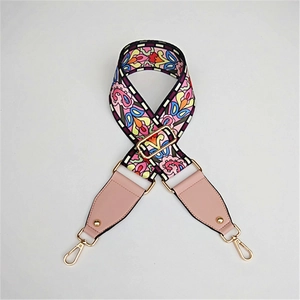 Close-up of colorful ethnic floral jacquard bag strap with pink leather and gold metal hardware