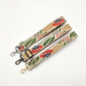 Detailed view of adjustable floral webbing straps with gold, silver and black metal hooks