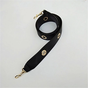 Detail of black PU leather shoulder strap with gold eyelets and metal lobster clasps