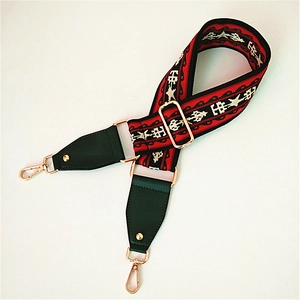 Close-up of ethnic style embroidered bag strap with red geometric pattern and metal hooks