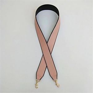 Dettaglio di un'ampia tracolla in pelle PU rosa e nera con ganci in metallo dorato