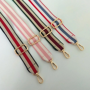 Detail of adjustable canvas crossbody straps in four striped patterns with gold hardware