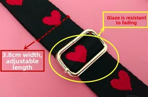 Detail of 3.8cm wide black bag strap with red heart embroidery and gold metal buckle