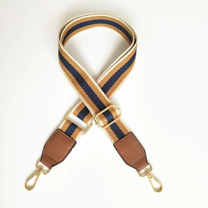 Detail of wide woven strap with ethnic pattern, gold metal hooks and leather ends