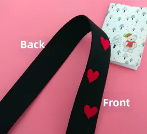 Close-up of heart embroidered wide bag strap showing front and back texture on pink background