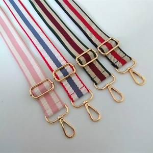 Close-up of diverse woven bag straps with high-gloss gold metal buckles and hooks