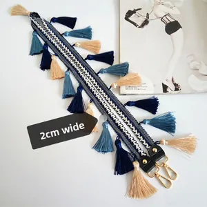 Détail d'une bandoulière tissée de 2cm avec motifs géométriques et pompons bohèmes