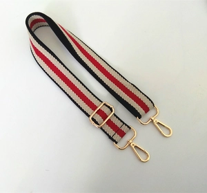 Detail of red black and beige striped canvas strap with golden swivel lobster clasps