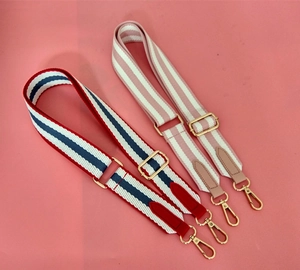 Detail view of ethnic style wide fabric bag straps with gold metal hooks on pink base