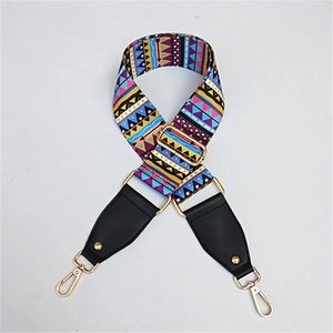 Detail of bohemian geometric pattern bag strap with gold lobster clasps and black leather