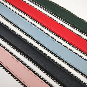 Close-up of colorful leather bag straps featuring decorative silver metal bead chain edges
